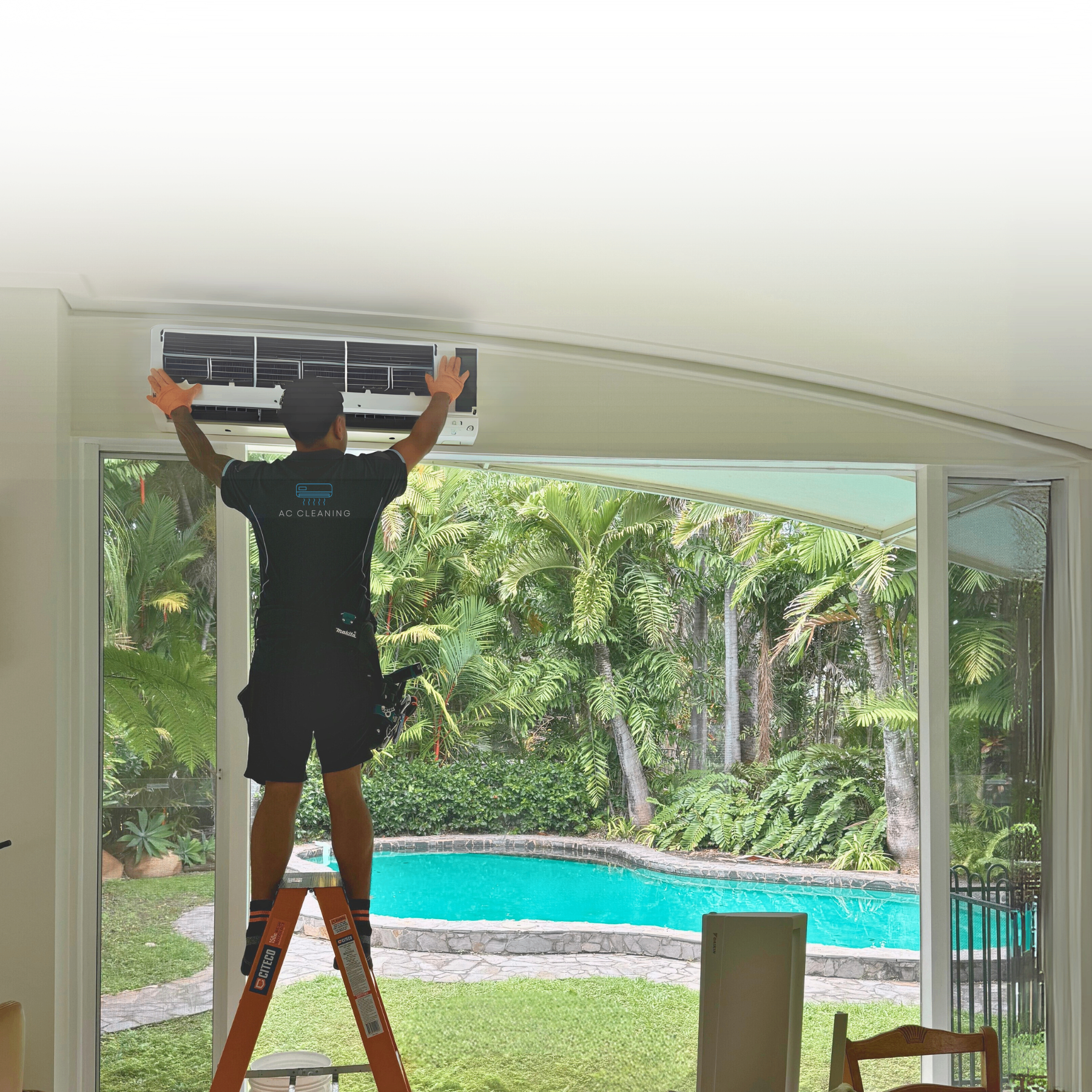 Professional AC technician cleaning air conditioning unit with tropical pool background